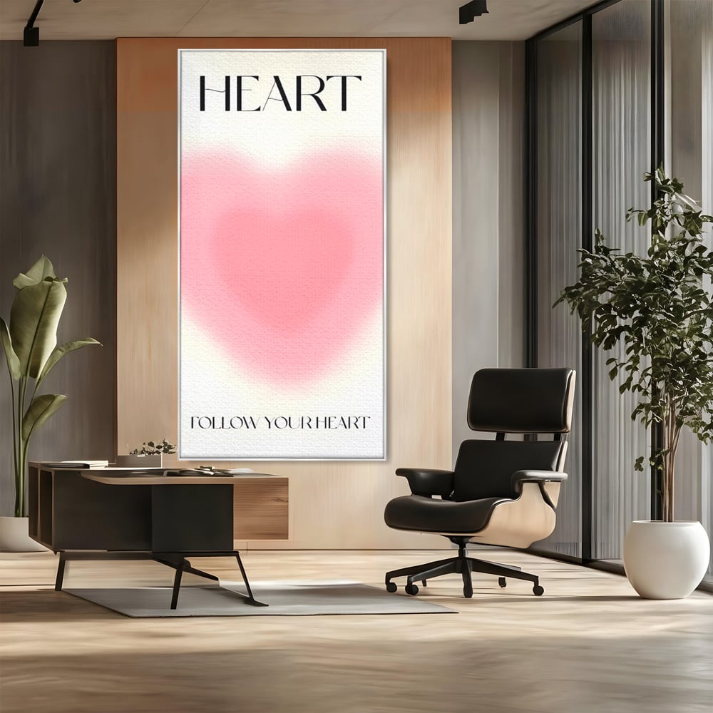 Tablou canvas cu tablou vertical cu inima roz blurata, in rama de aluminiu argintiu, pe perete intr-un birou